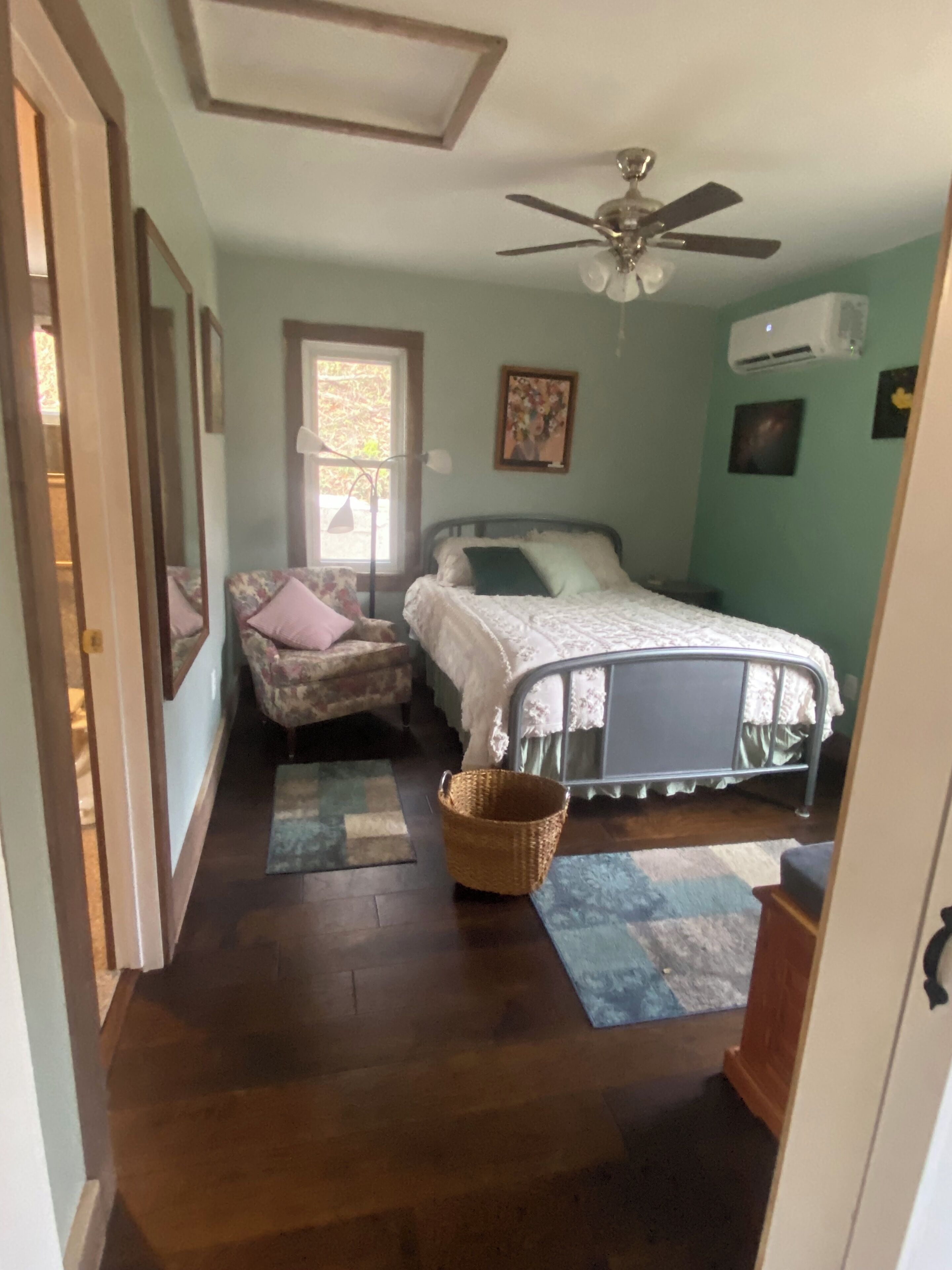 A bedroom with a bed, a chair, a ceiling fan, and a window.