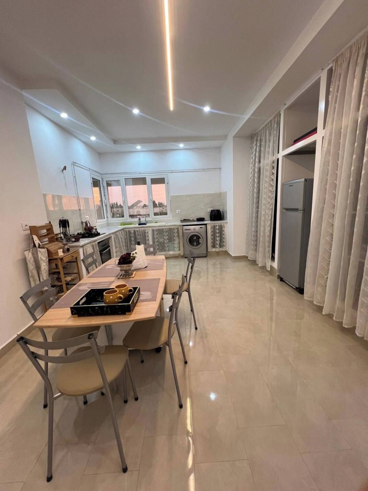 A modern kitchen with a dining area, a washing machine, and a refrigerator.
