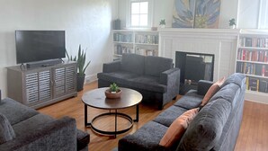 Una sala de estar con televisor, sofás, una mesa de centro, chimenea y estanterías.