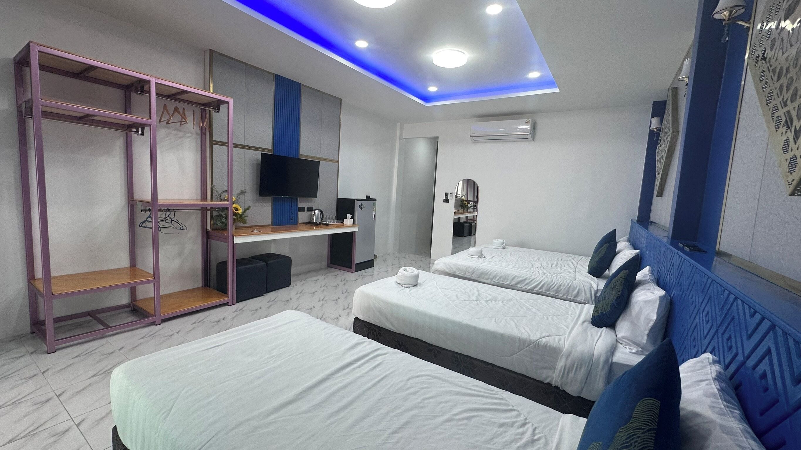 Habitación de hotel con dos camas, televisión, armario y escritorio con ordenador.