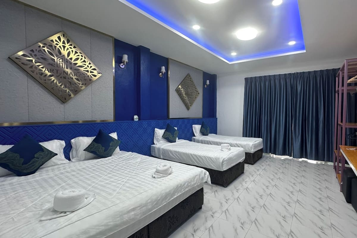 Quarto de hotel com duas camas, uma escrivaninha, um espelho e um ornamento decorativo na parede.