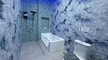 A modern bathroom with a marble wall, a glass-enclosed shower, a freestanding bathtub, and a toilet.