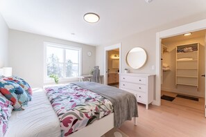 Een slaapkamer met een bed, nachtkastje, kaptafel en inloopkast.
