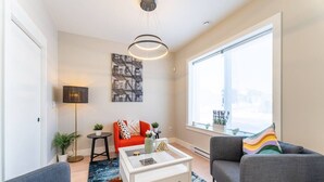 A modern living room with a sofa, armchairs, a coffee table, and a large window.
