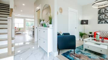 Un salon moderne avec un canapé bleu, une table basse blanche et un tapis aux couleurs vives.