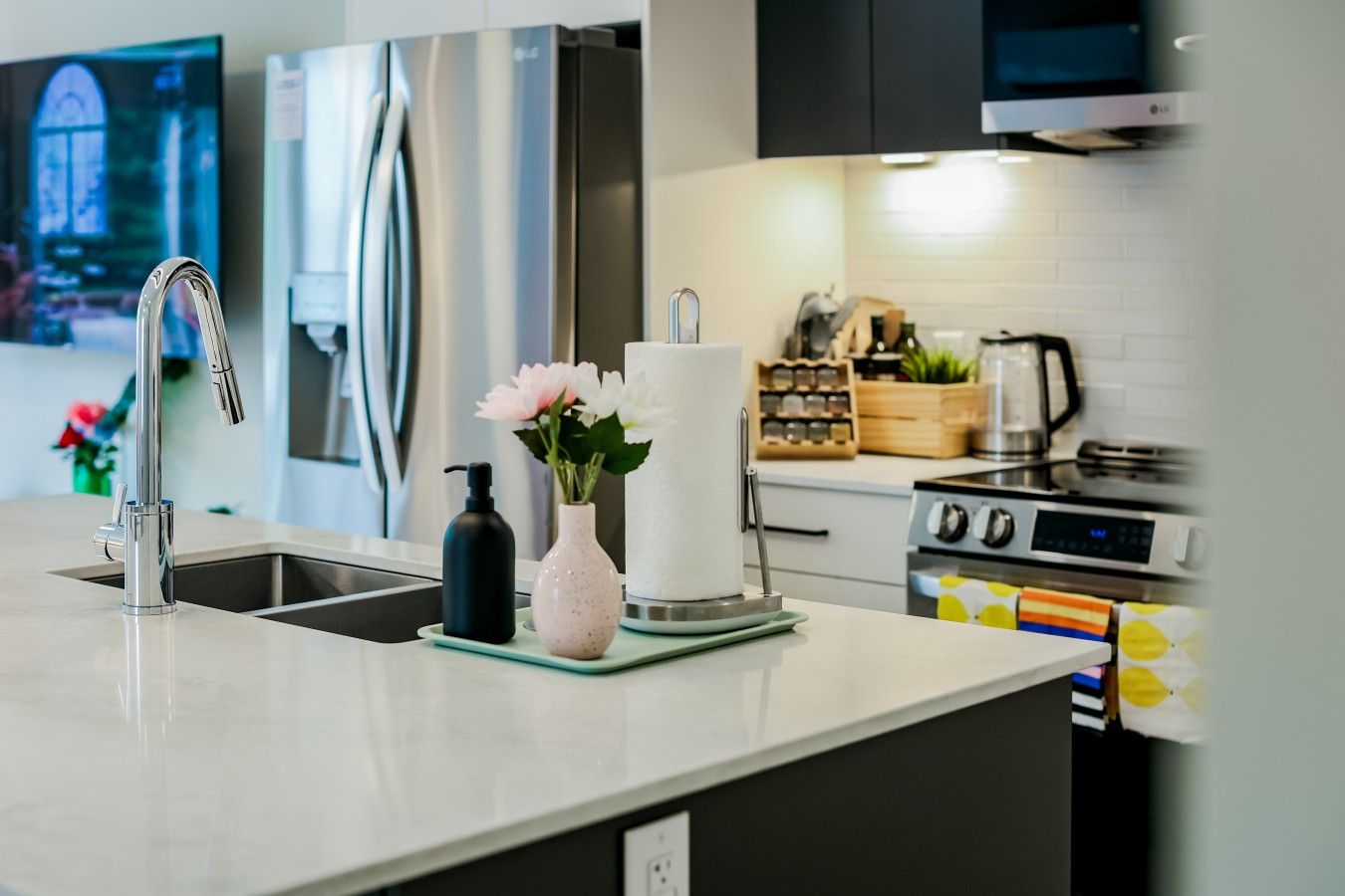 A modern kitchen with stainless steel appliances, a sink, and a countertop with a vase of flowers.