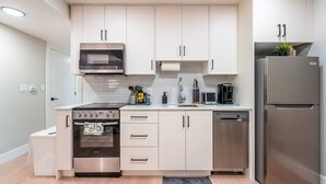 A modern kitchen with white cabinets, stainless steel appliances, and a built-in oven. - New Lux 2BR Bright & Spacious Walk-Out Suite in Halifax (Halifax)
