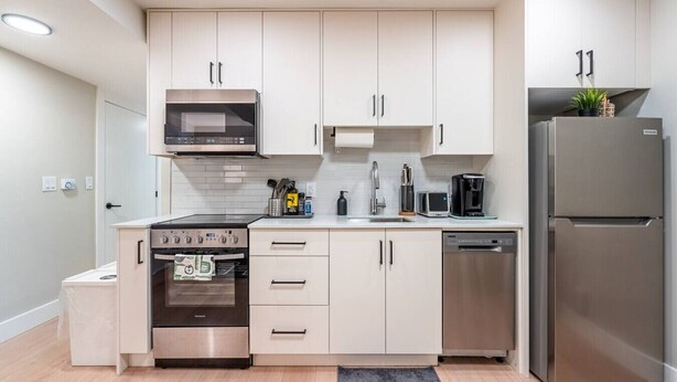 A modern kitchen with white cabinets, stainless steel appliances, and a built-in oven.