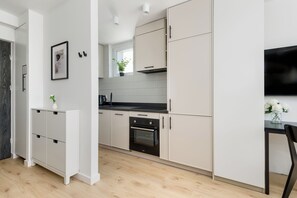 A modern kitchen with white cabinetry, a built-in oven, and a black countertop. - Coffee Mood by Kairos Apartments (Gliwice)