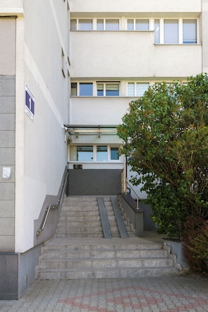 A set of concrete steps leading to a building entrance, a metal handrail, and a small tree to the right. - Coffee Mood by Kairos Apartments (Gliwice)
