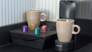 To kaffekopper på en sort bakke med en Krups kaffemaskine ved siden af.
