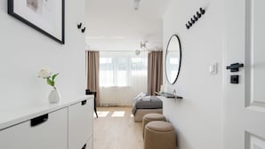 Una habitación de hotel moderna con cama, mesita de noche, espejo y un pequeño taburete.