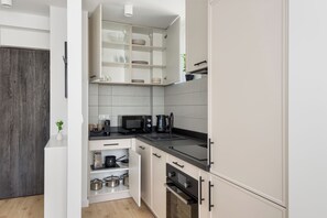 A modern kitchen with white cabinetry, a black countertop, and a microwave. - Coffee Mood by Kairos Apartments (Gliwice)