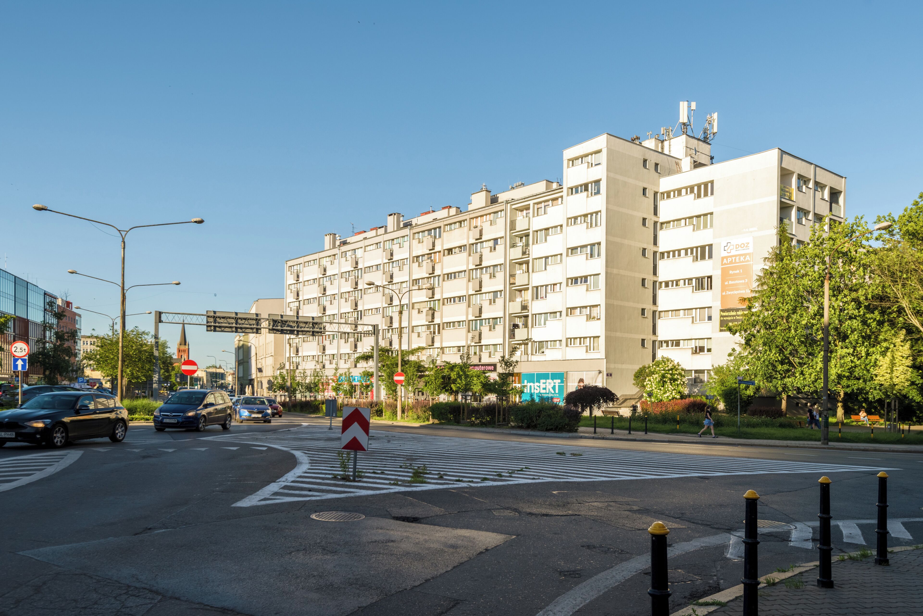 A multi-story building with a modern architectural style, a pedestrian crossing, and a clear blue sky.