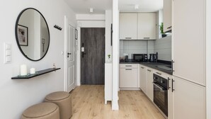 Una cocina moderna con armarios blancos, encimera negra y suelo de madera.
