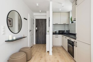 Una cucina moderna con mobili bianchi, un piano di lavoro nero e un pavimento in legno.