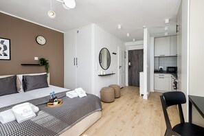 Una camera d'albergo moderna con un letto, un comodino e vista sull'angolo cottura.