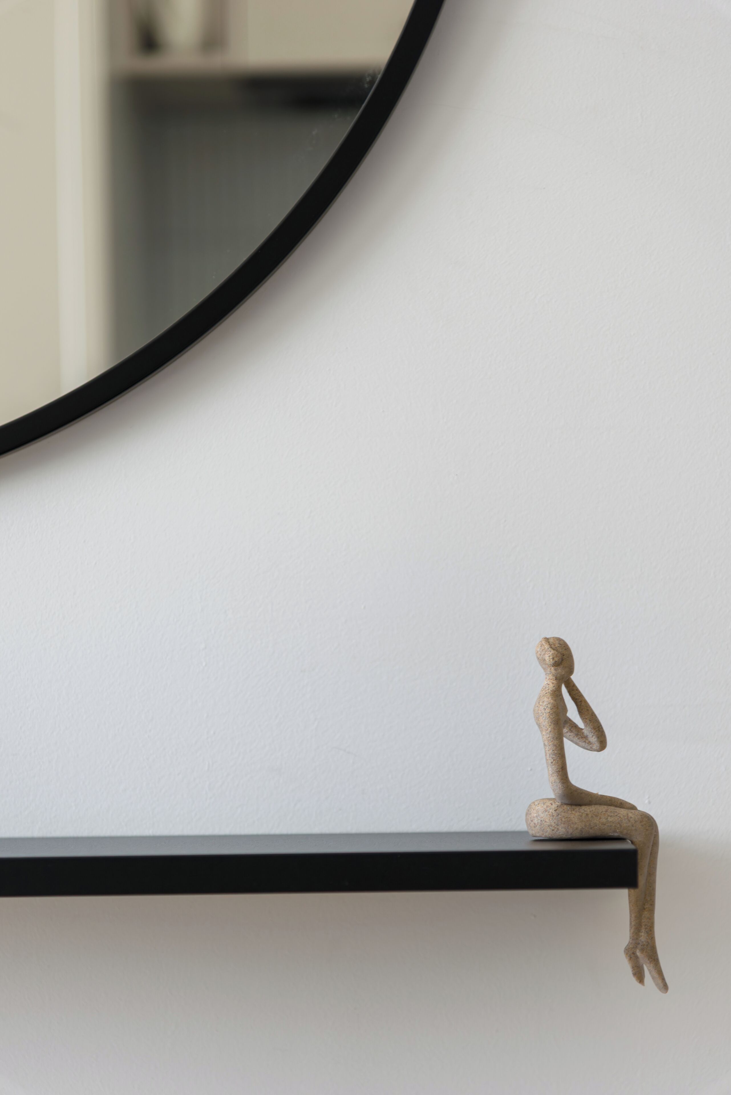 A minimalist sculpture on a black shelf against a white wall.