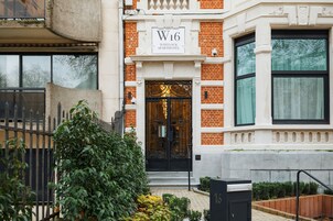 A brick building with a black wrought iron gate and a sign reading "W16 WHITLOCK APARTHOTEL".