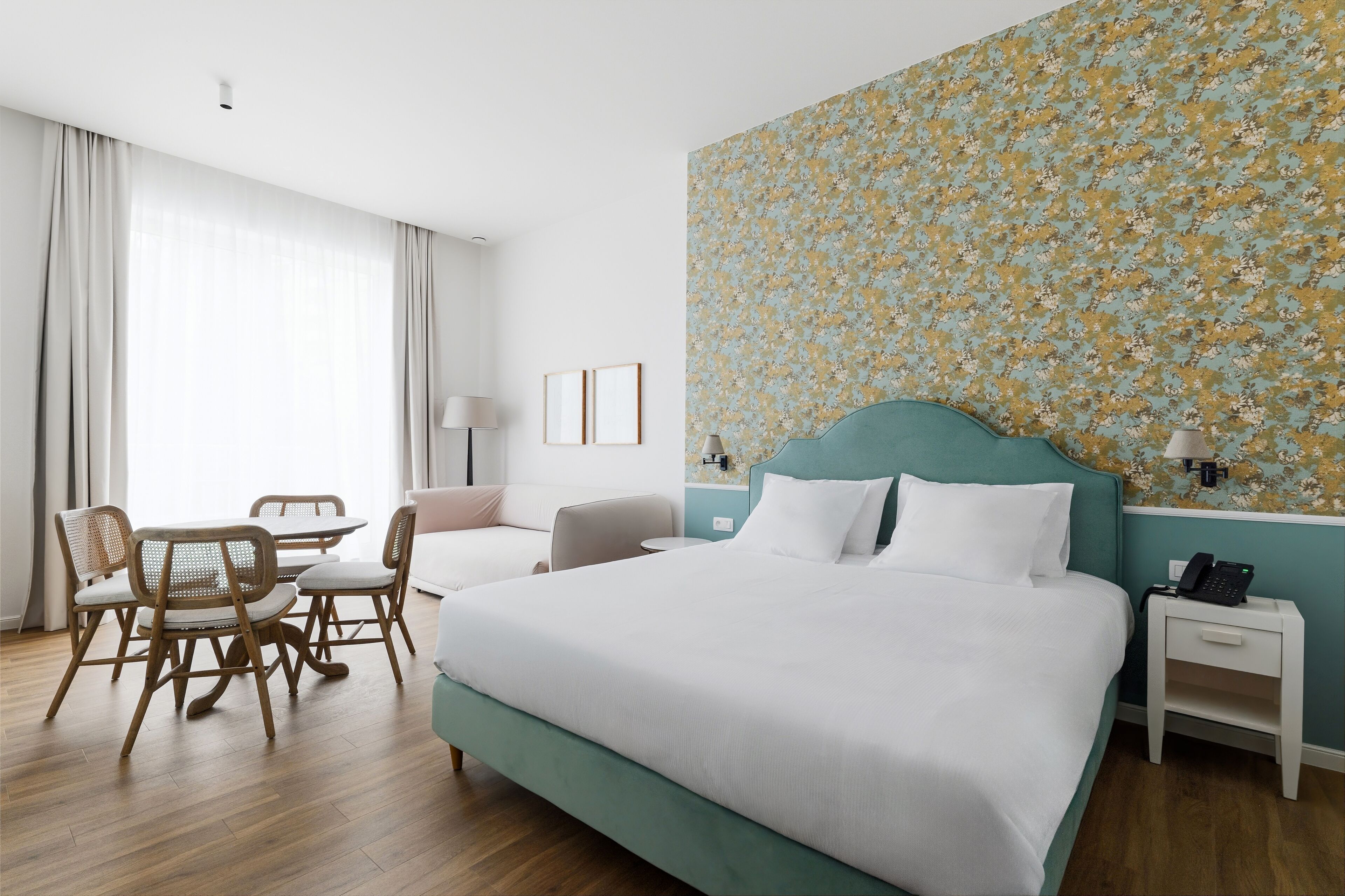 A hotel room with a bed, a desk, a chair, and a dining table.