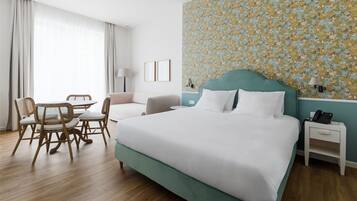 A hotel room with a bed, a desk, a chair, and a dining table.