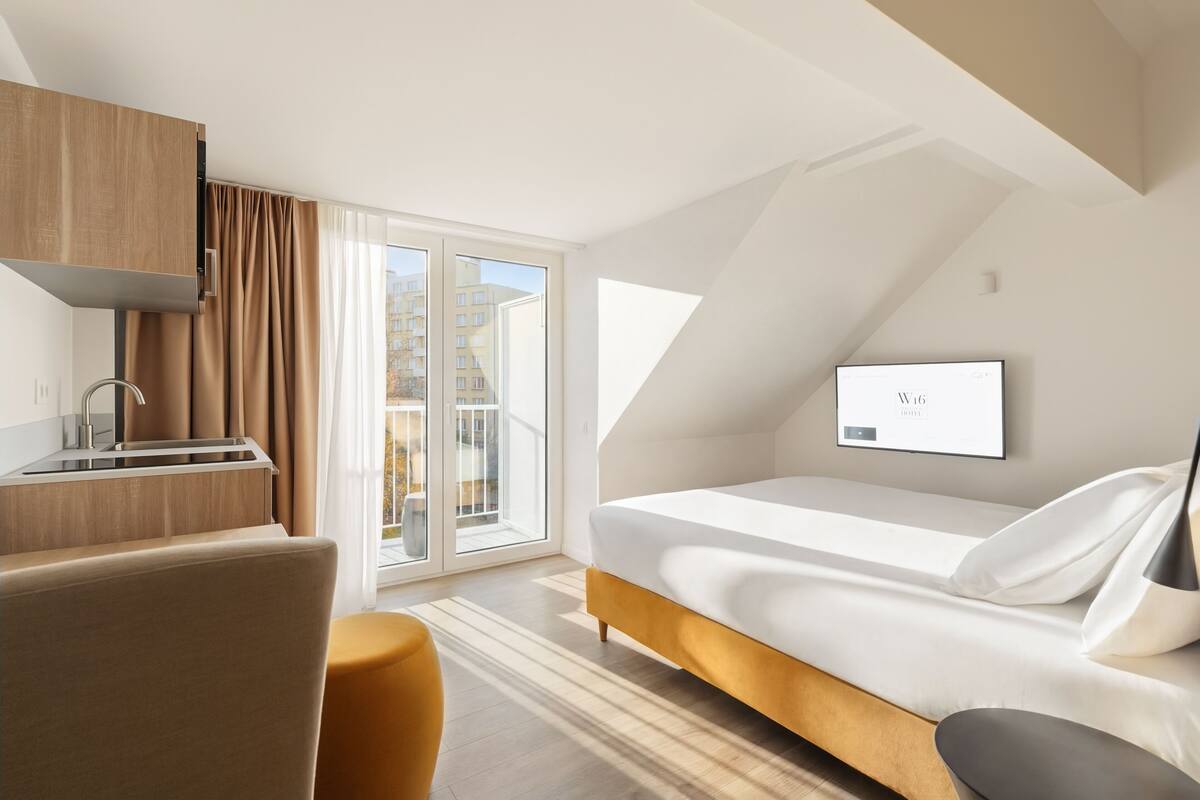 Een moderne hotelkamer met een bed, een bureau en een groot raam met uitzicht op de stad.