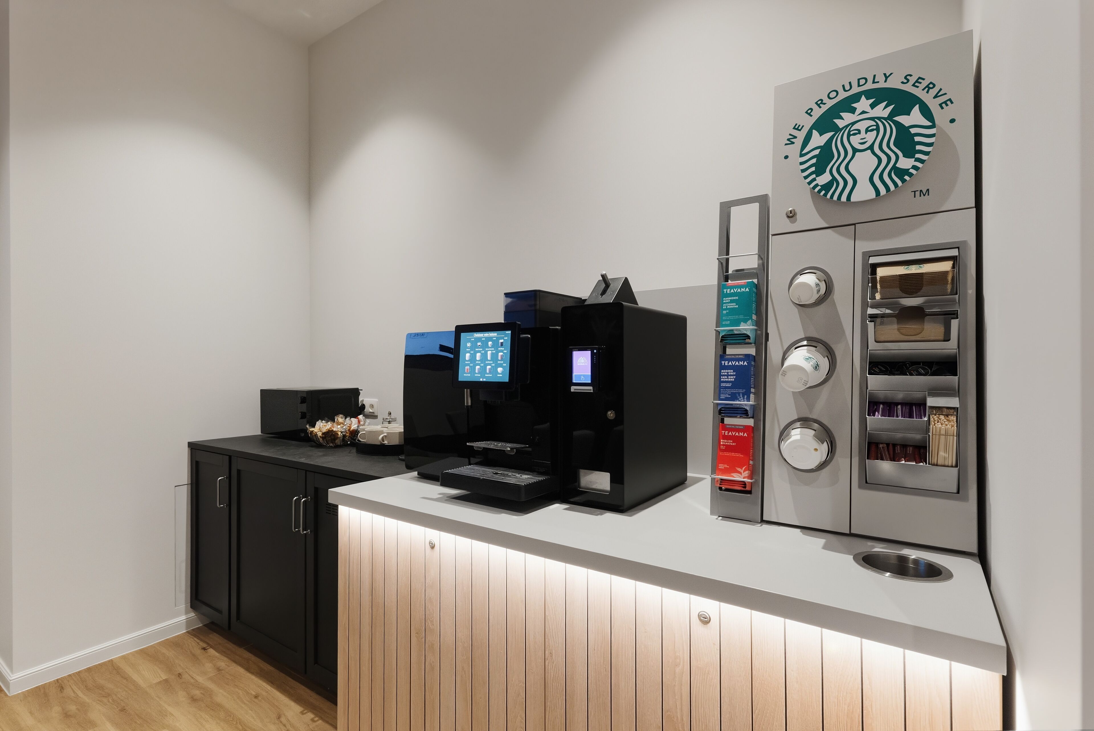 Una cocina moderna con cafetera, dispensador de té y refrigerador empotrado.