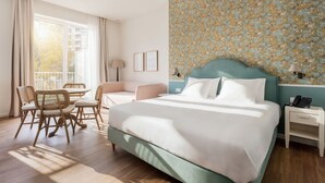 Een hotelkamer met een groot bed, een bureau, een stoel en een balkon met gordijnen.