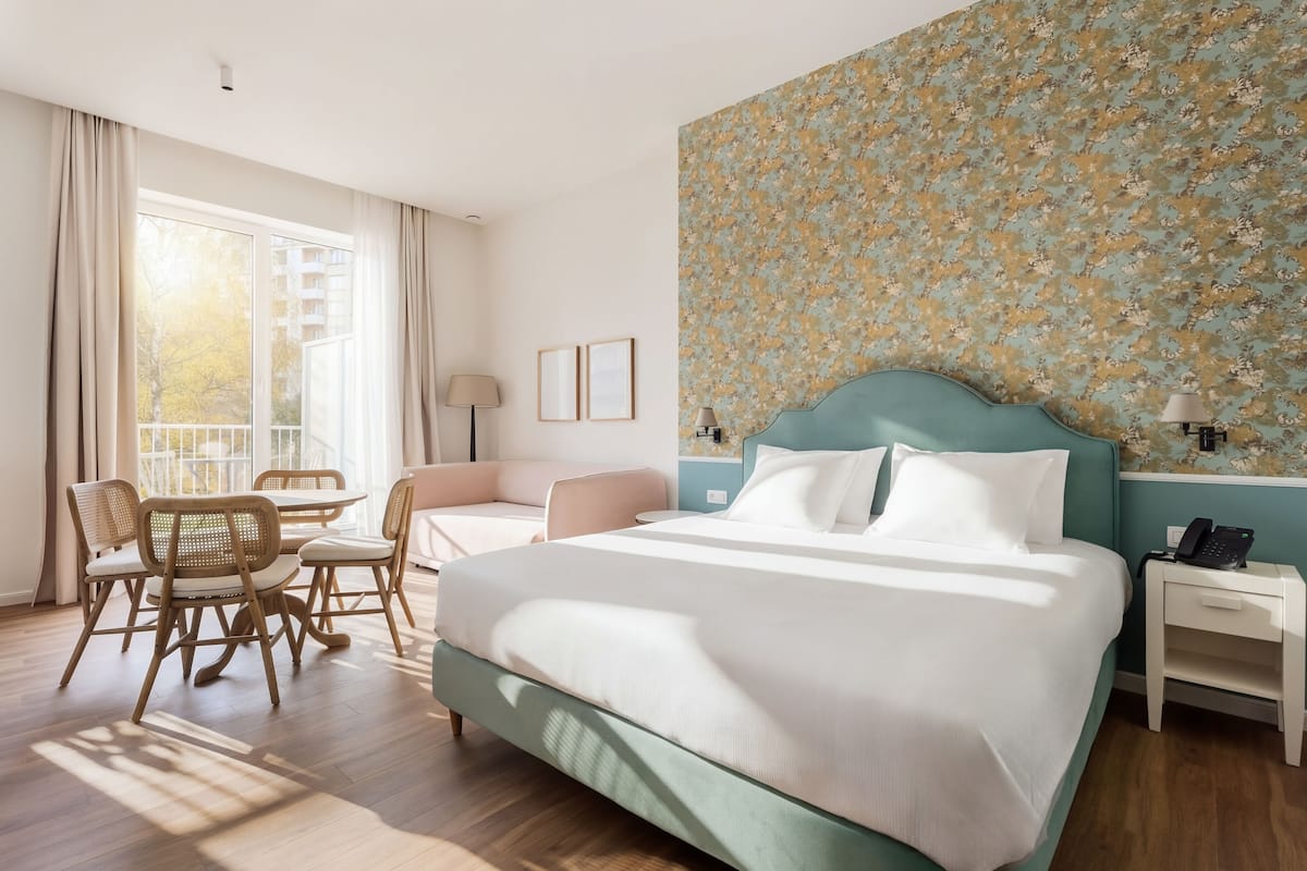 Een hotelkamer met een groot bed, een bureau, een stoel en een balkon met gordijnen.