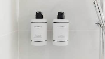 Dos botellas blancas de productos capilares CODAGE Paris sobre una pared de azulejos blancos.