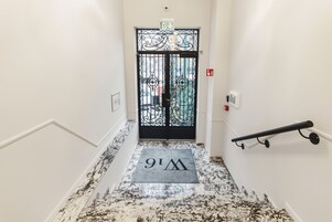 A marble staircase leading to a black metal door with a doormat reading "W11".