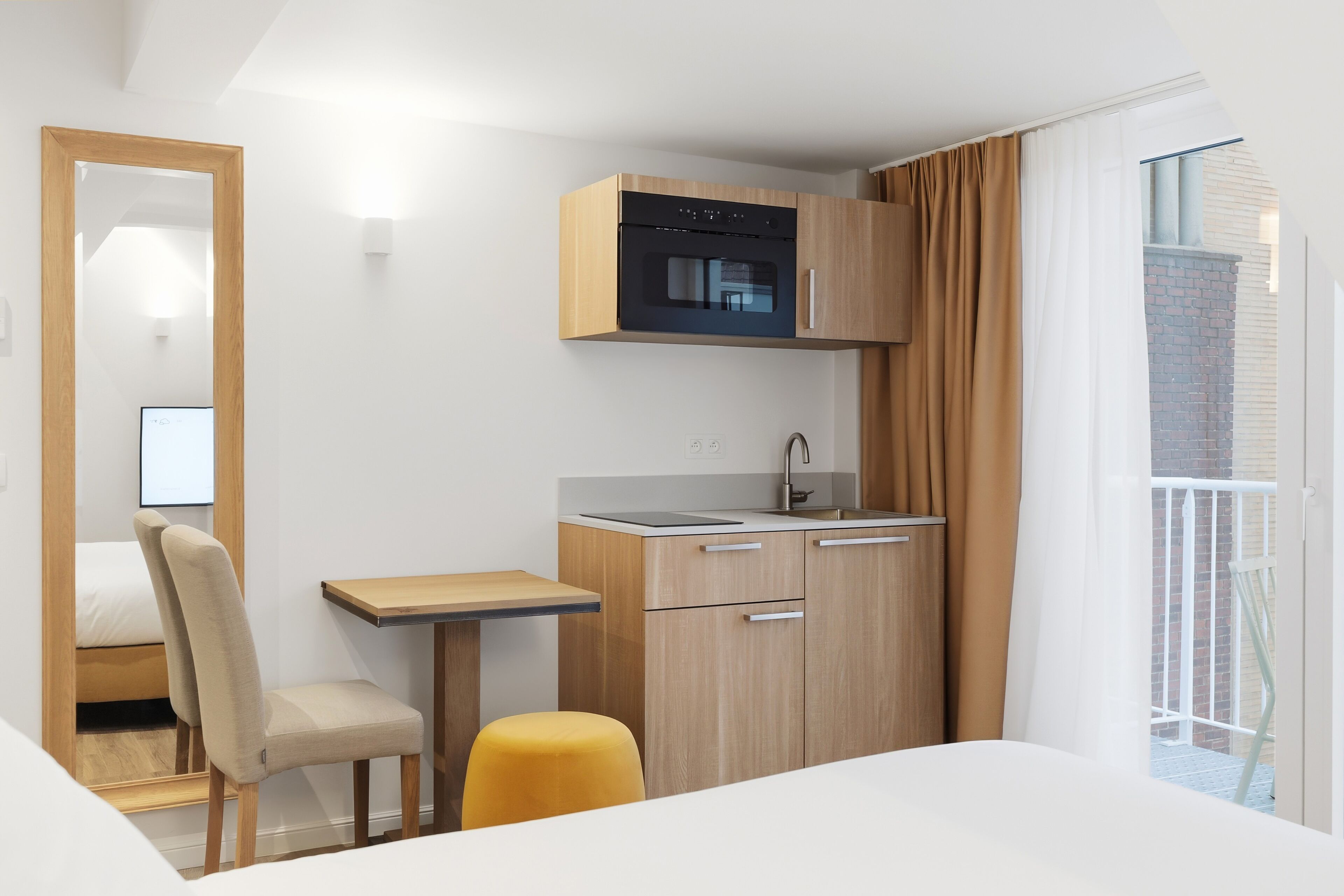 A compact kitchen with a built-in oven, a small dining table, and a chair.