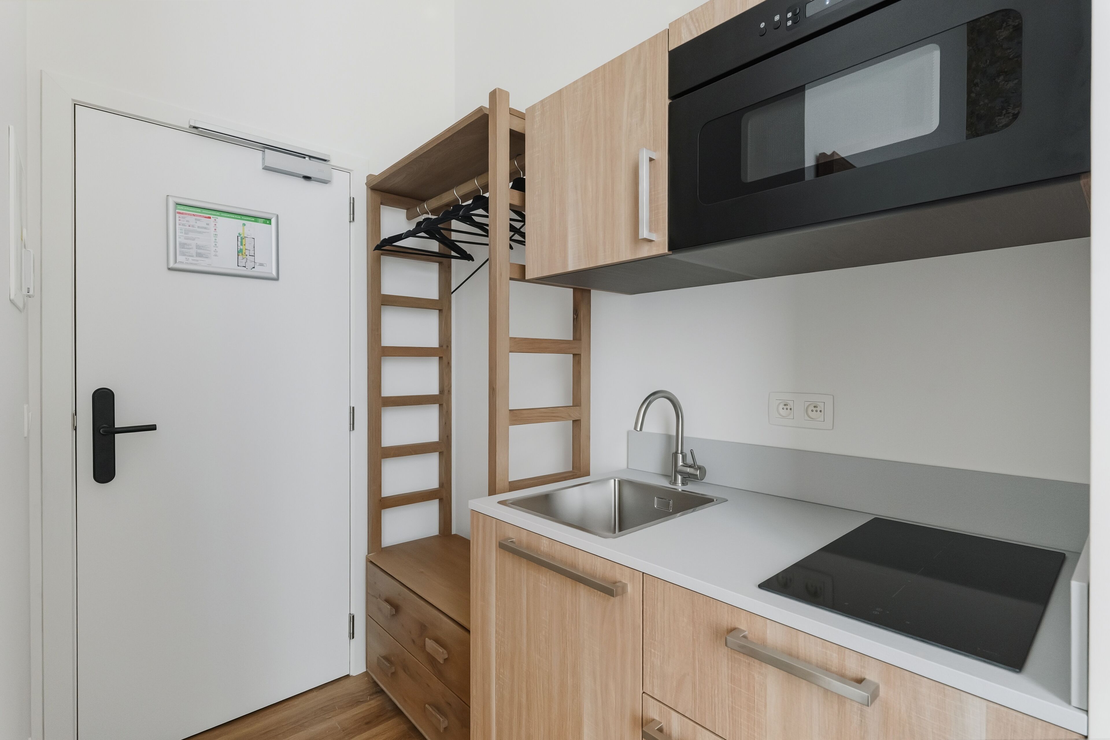 A compact kitchen with a built-in microwave, a sink, and wooden cabinets.