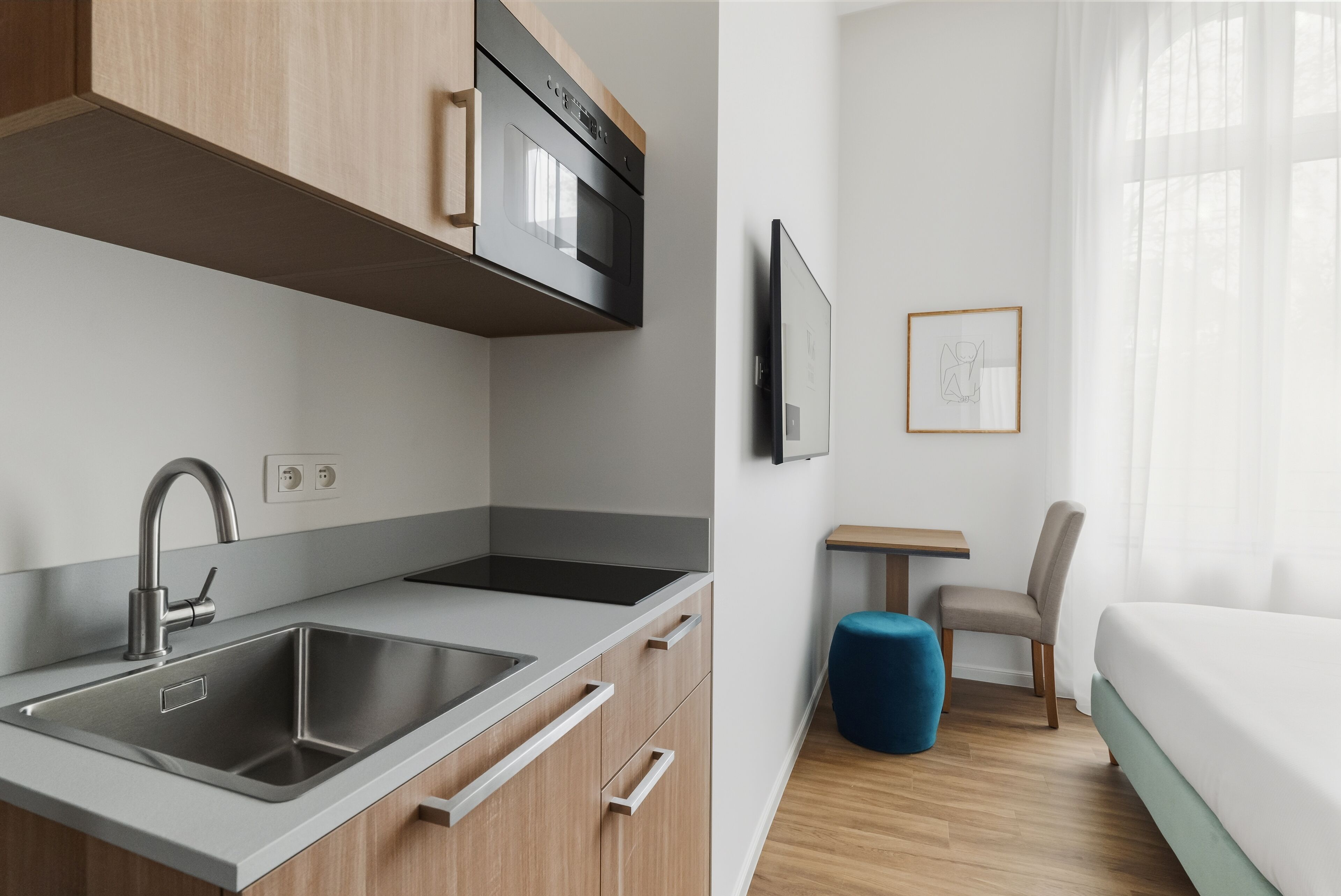 Una cocina moderna con un lavamanos doble, horno empotrado y un pequeño comedor con mesa y silla.