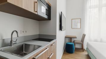 Una cocina moderna con un lavamanos doble, horno empotrado y un pequeño comedor con mesa y silla.