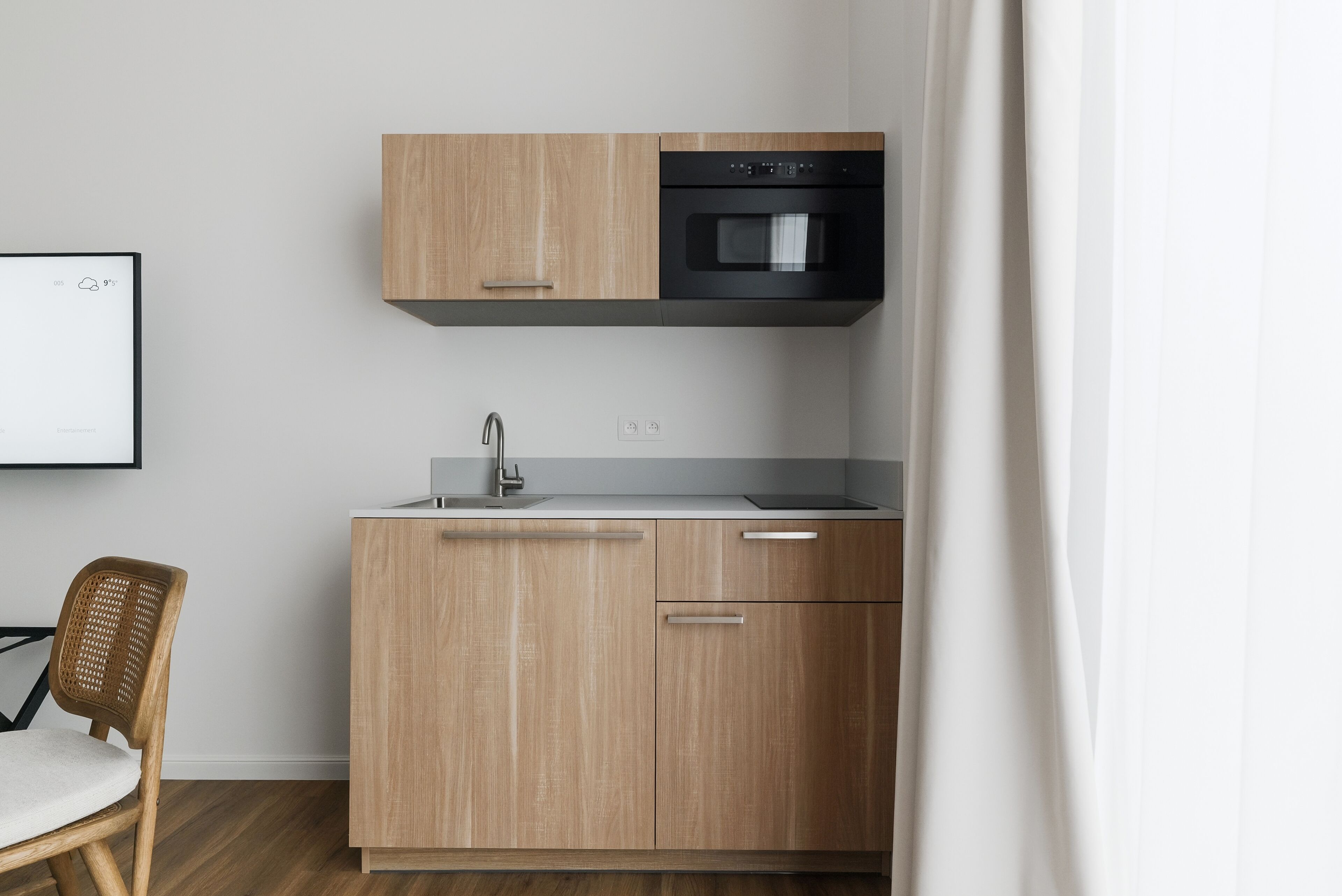 Una cocina moderna con armarios de madera, un horno negro y un lavamanos de acero inoxidable.
