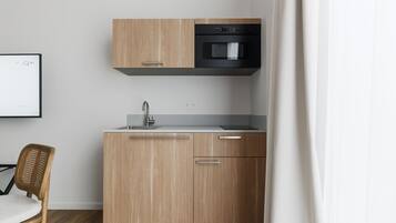 Una cocina moderna con armarios de madera, un horno negro y un lavamanos de acero inoxidable.