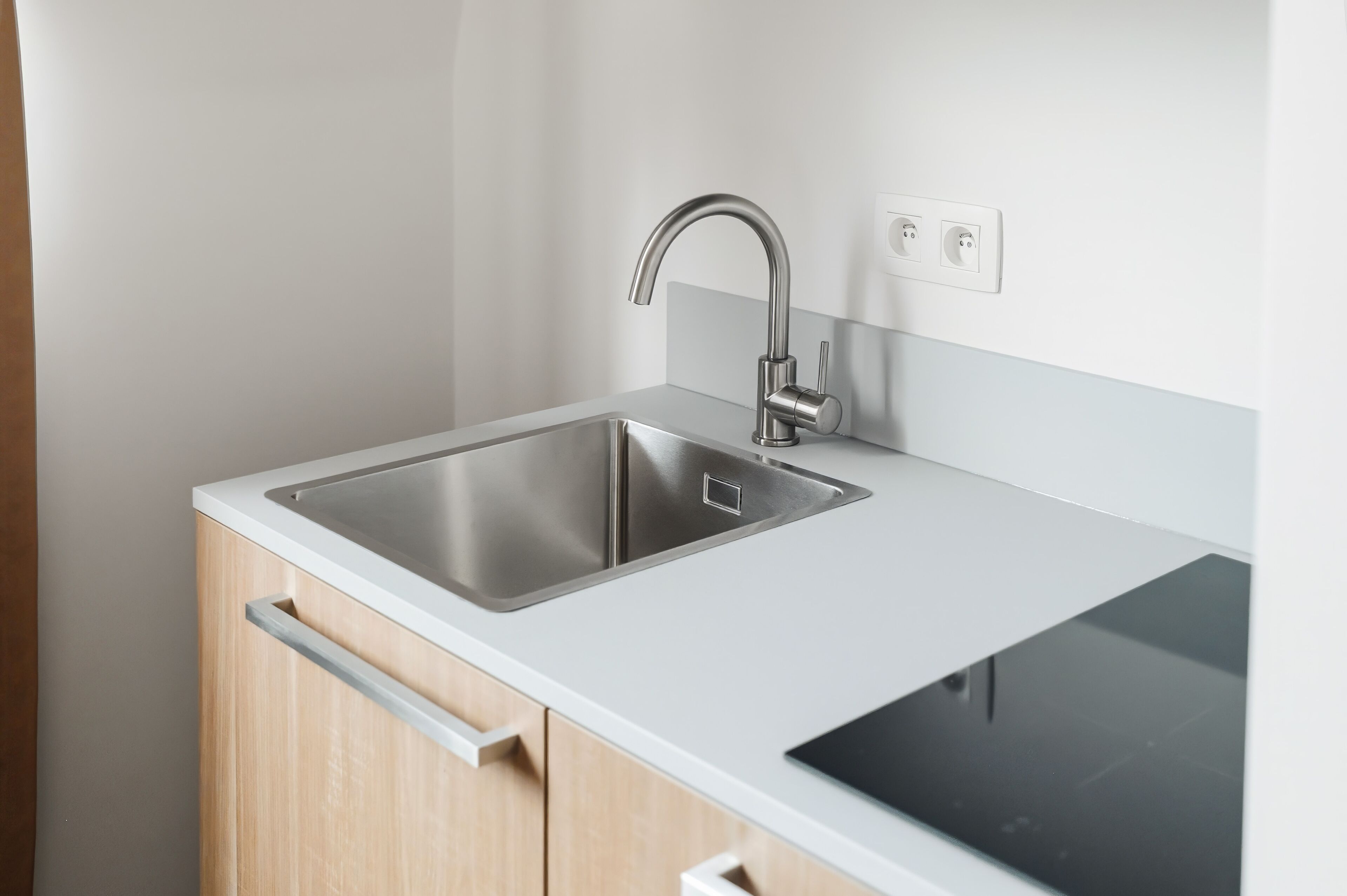 Una cocina moderna con un lavamanos de acero inoxidable, horno empotrado y armarios de madera.