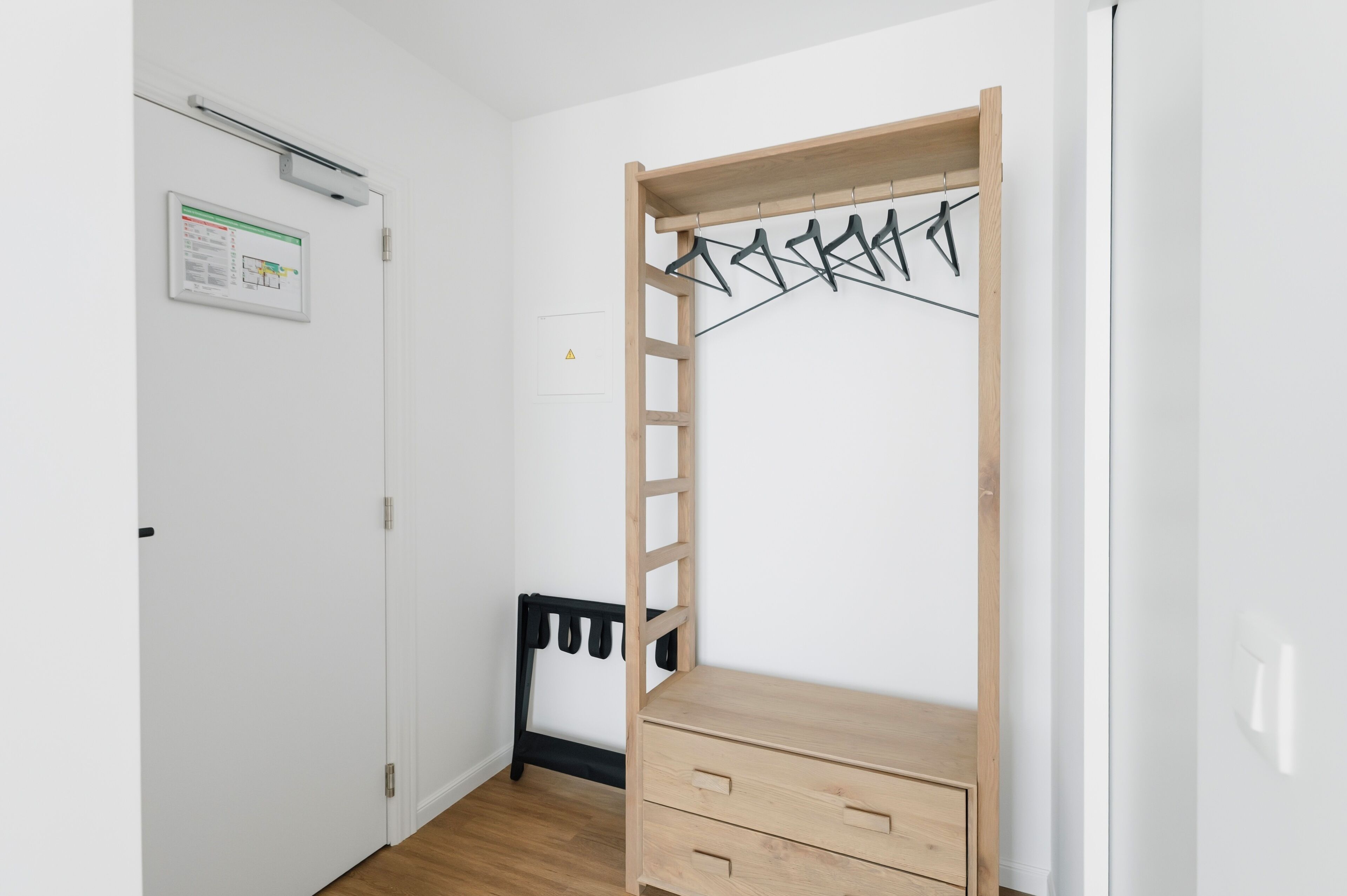 A room with a wooden wardrobe, a black radiator, and a white door.