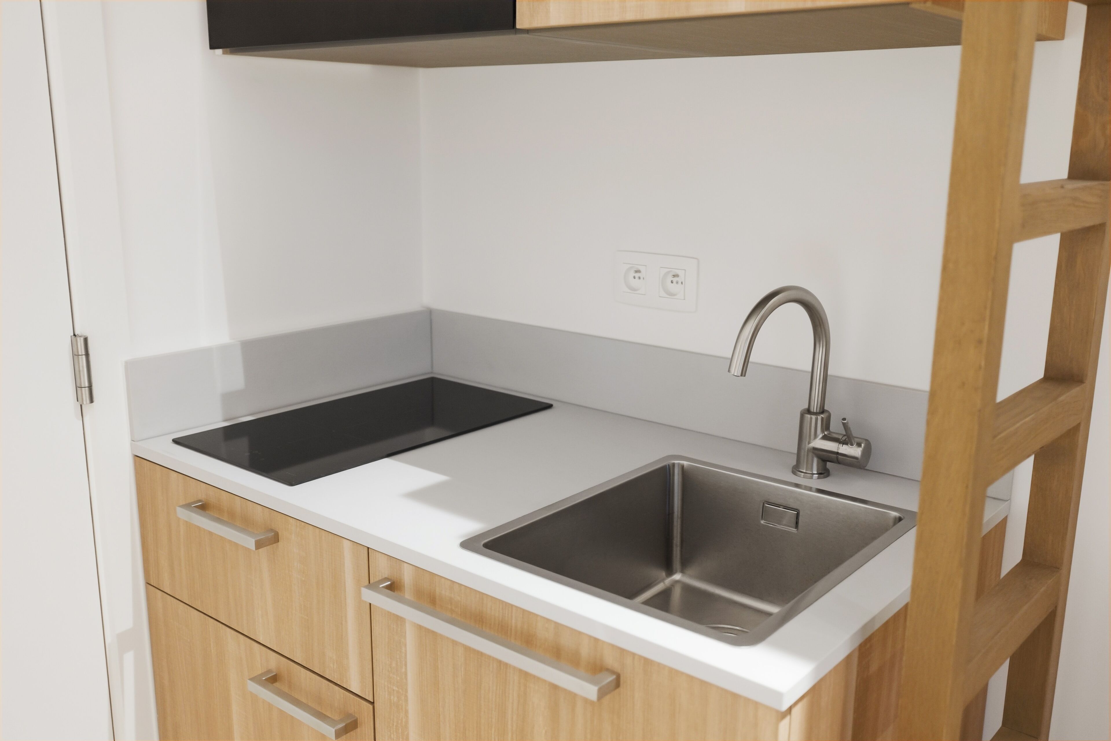 A modern kitchen with a double sink, wooden cabinets, and a white countertop.
