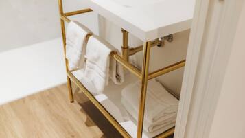 Een badkamer met een witte wastafel en gouden details, waaronder een handdoekrek en een wastafelmeubel.