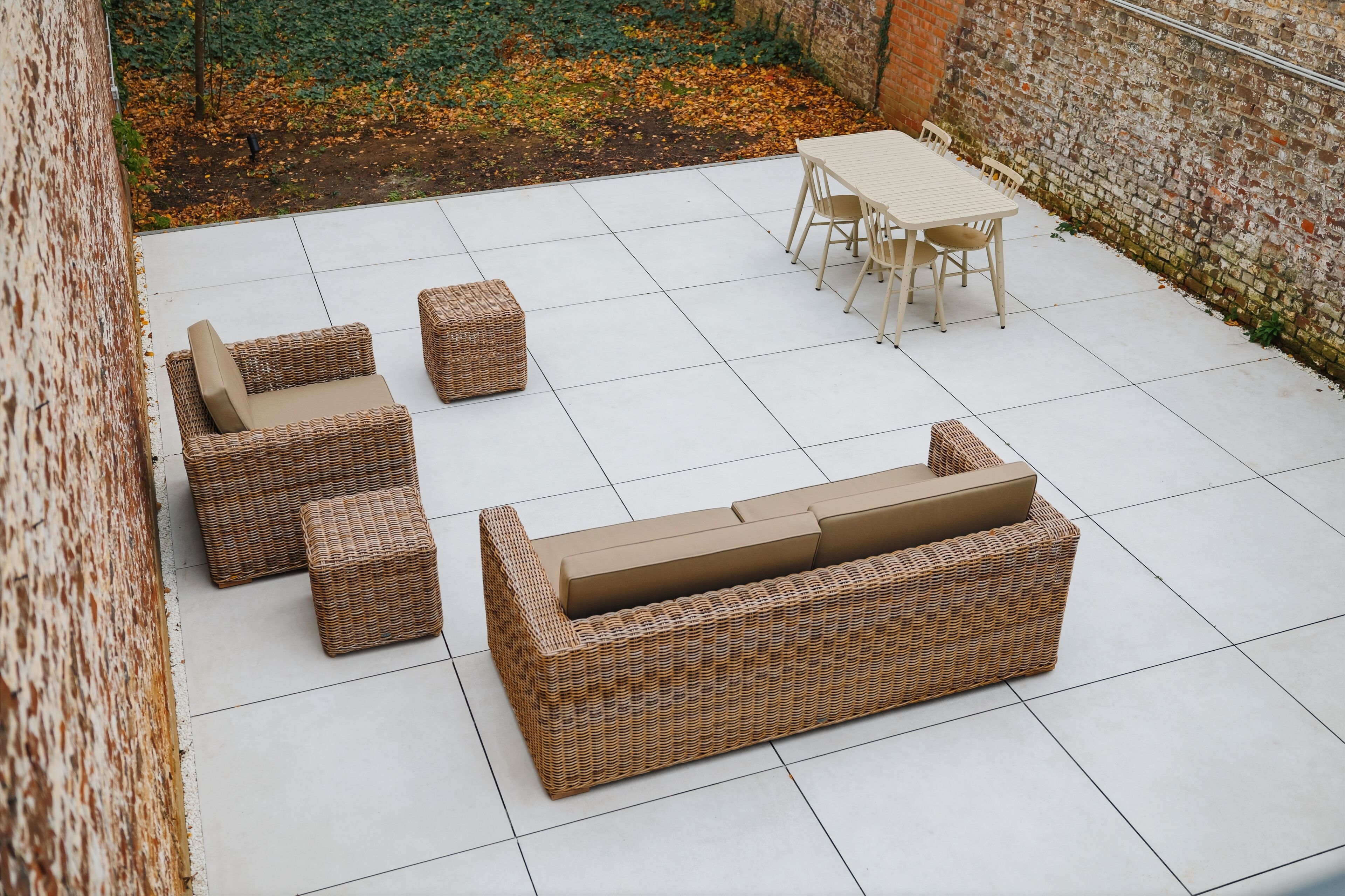Une terrasse dotée de meubles en osier, notamment d’un canapé et de fauteuils, ainsi que d’une table.