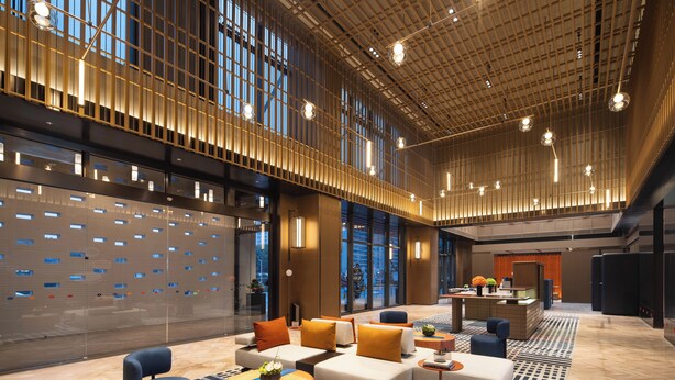 A spacious lobby with a modern design, featuring a seating area with sofas and armchairs, a reception desk, and large windows providing views of the city. - Hampton by Hilton Cixi Guanhaiwei (Ningbo)