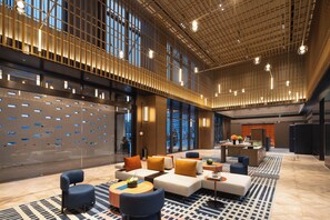 A spacious lobby with a modern design, featuring a seating area with sofas and armchairs, a reception desk, and large windows providing views of the city. - Hampton by Hilton Cixi Guanhaiwei (Ningbo)