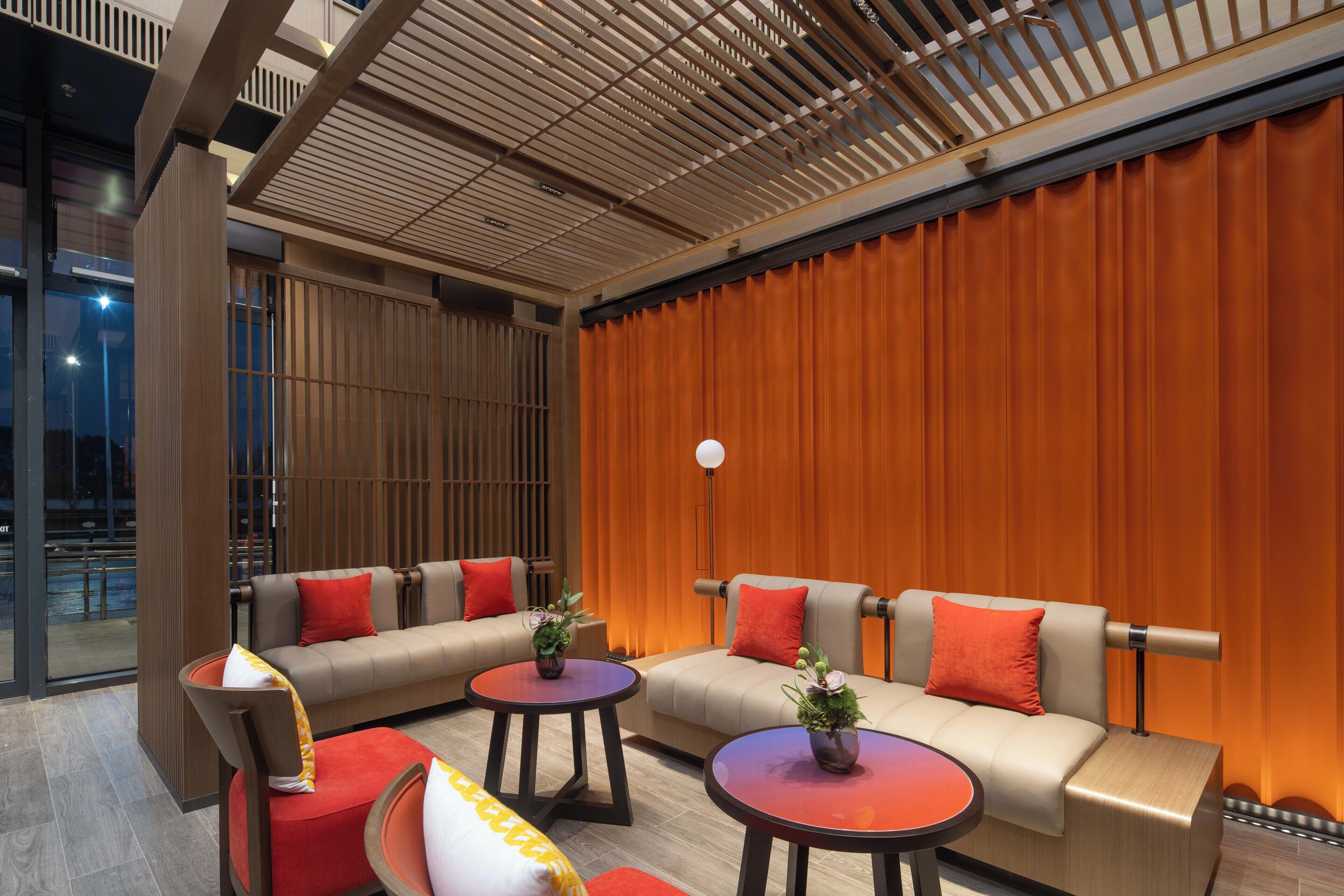 A modern lounge area with sofas, round tables, and a large curtain backdrop.