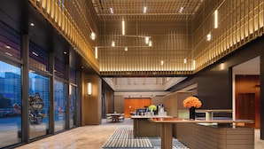 A modern lobby with a reception desk, seating area, and large windows offering views of the cityscape.