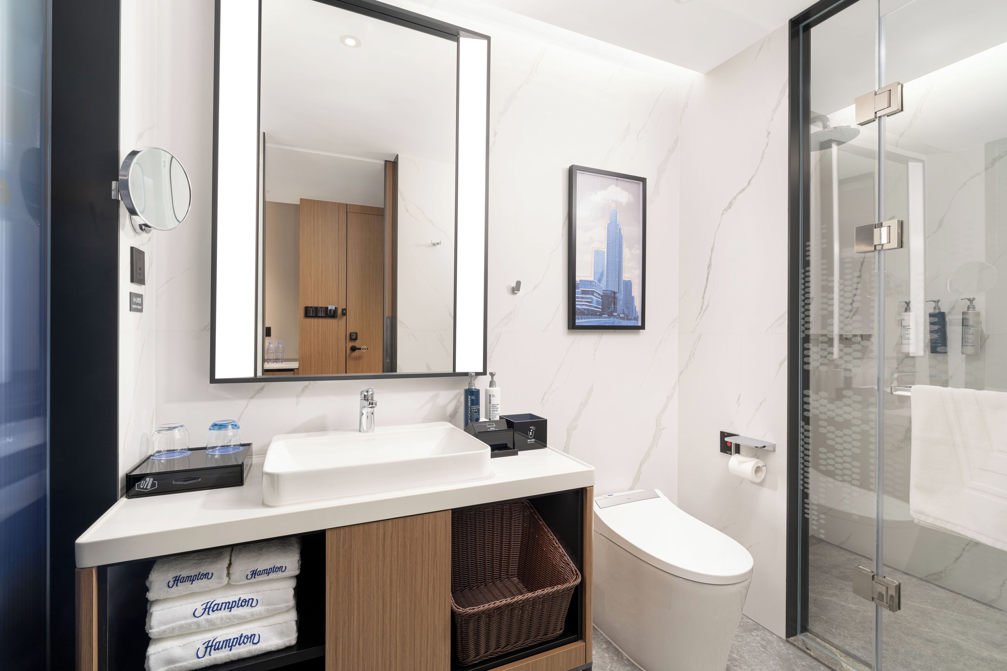 Un bany modern amb un mirall gran, un lavabo, un vàter i una dutxa amb envàs de vidre.