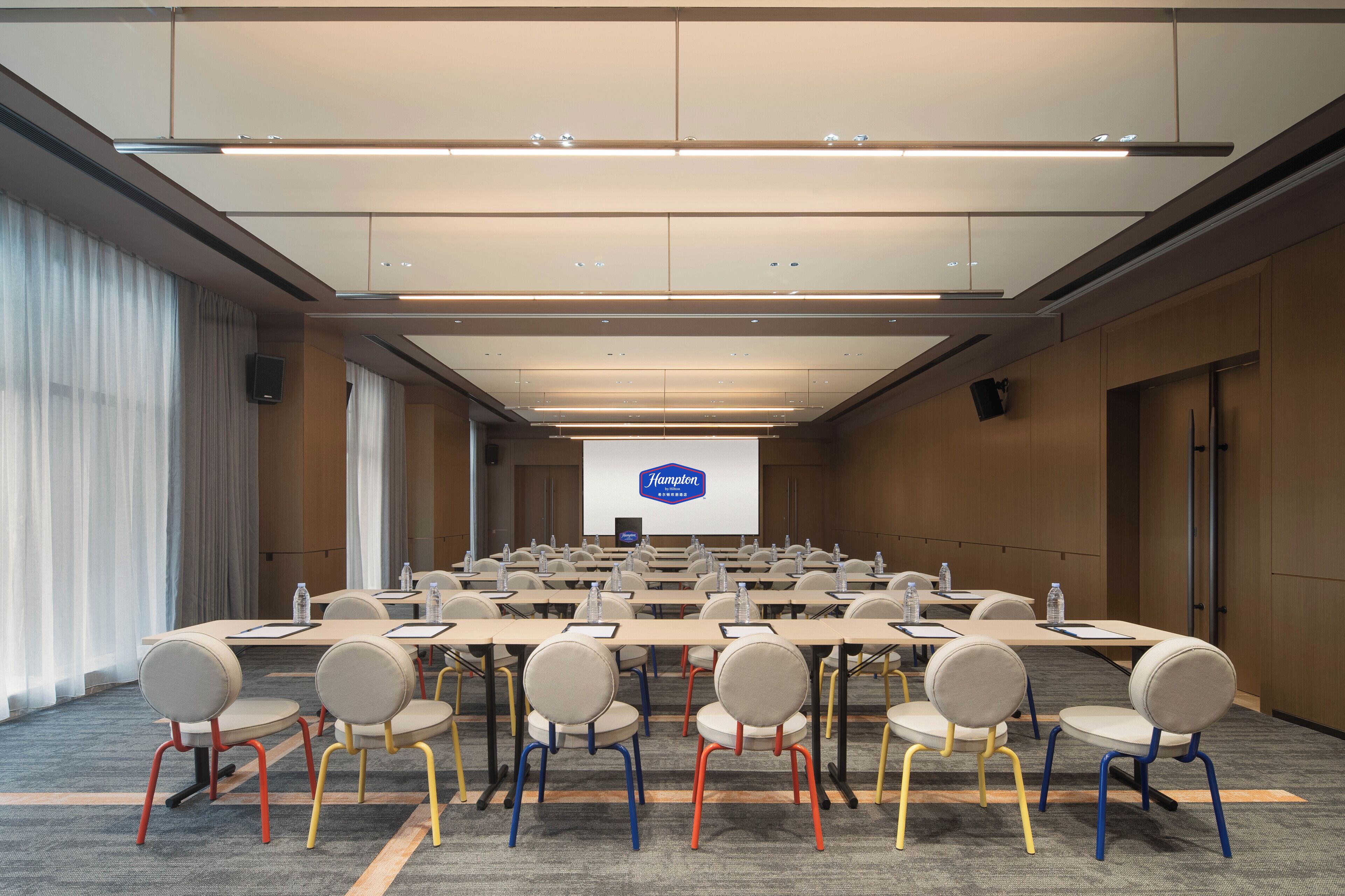 Una sala conferenze con un lungo tavolo, sedie e uno schermo per presentazioni.
