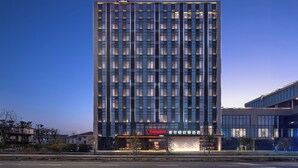 A modern hotel building with a prominent "Hampton" sign at the top and a "Hampton" sign at the entrance. - Hampton by Hilton Cixi Guanhaiwei (Ningbo)