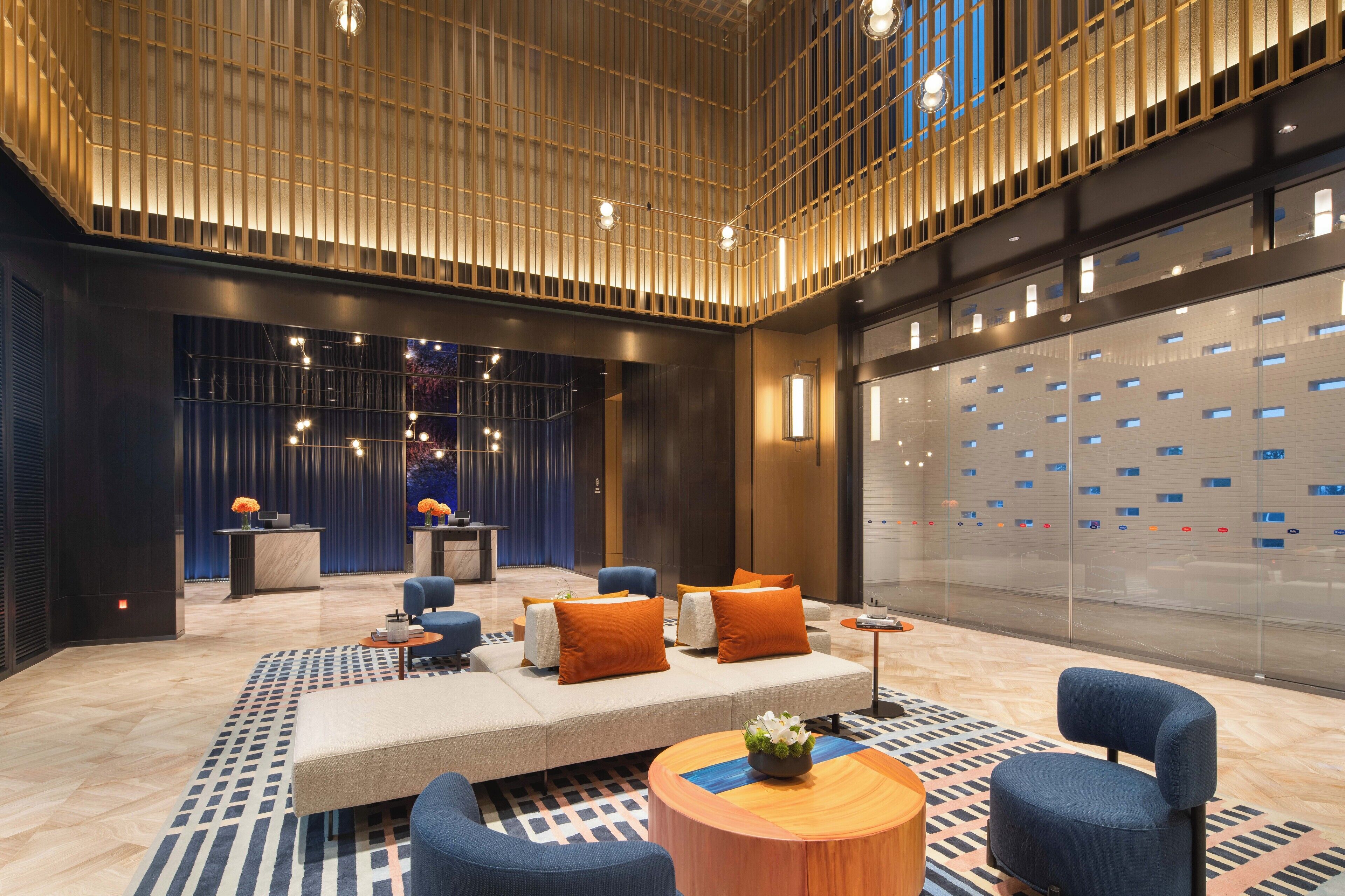 A modern lobby with a seating area, a reception desk, and a glass wall with a pattern.